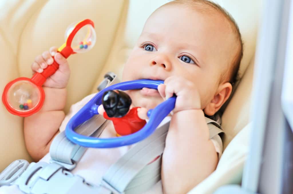 Babywippe 61 Baby in einer Babywippe mit Babyspielzeug