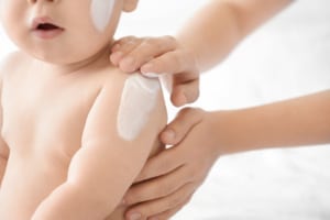 Babyerstausstattung 1 Baby wird Babylotion eingecremt